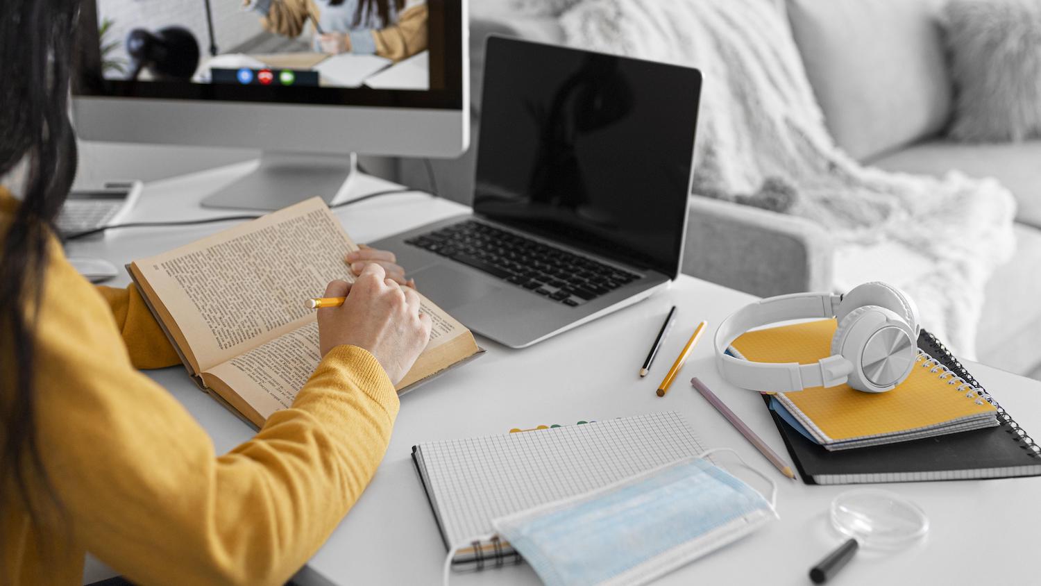 woman leaning against a couch looking at a laptop